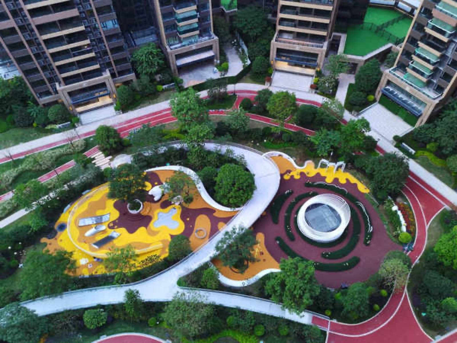 Aerial of the full residential compound with EPDM play zones and running paths